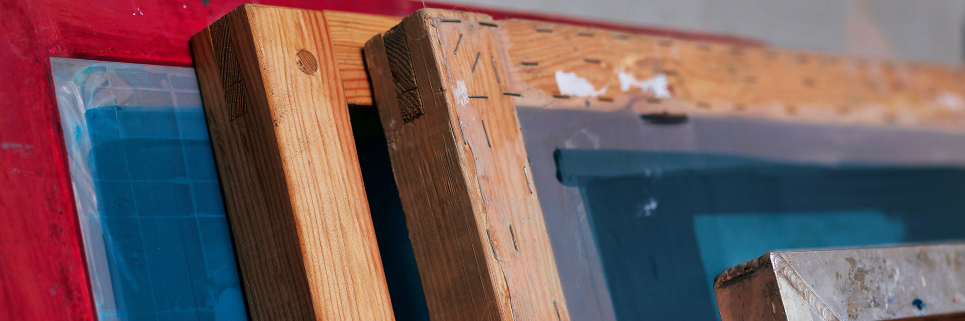 Fotograf: Ivan Martynov Fyra ramar, en röd, två träfärgade och en av metall som står lutade mot en vägg.